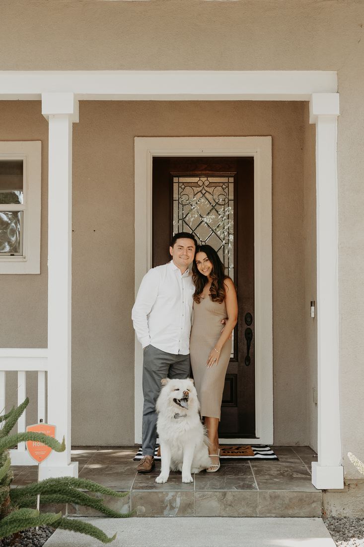 Couple with their dog at the front door of their new home