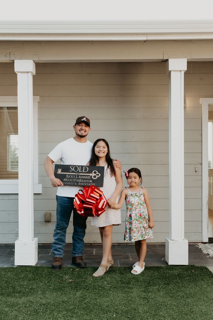 Family on the front porch with a new home sign