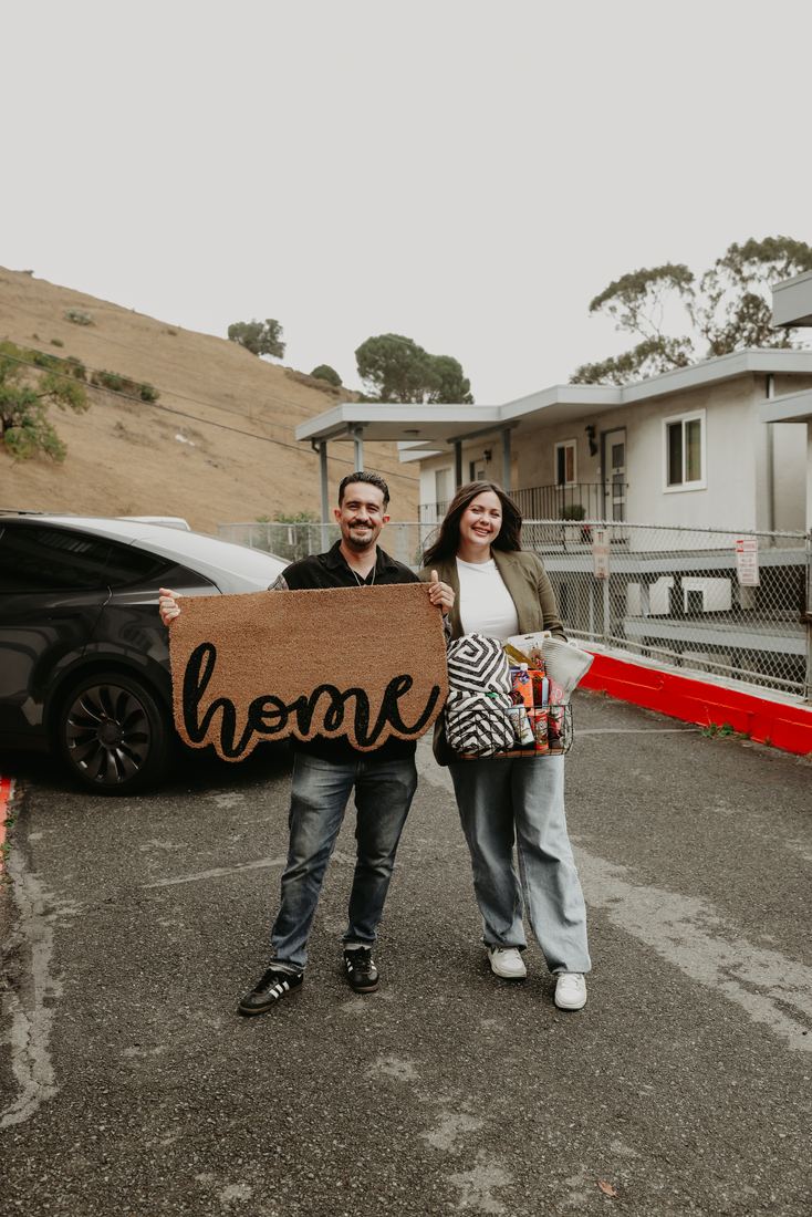 Couple holding a Home sign outside their new house